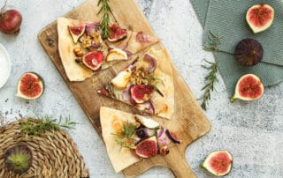Auf dem Bild ist ein vegetarischer Flammkuchen mit Ziegenkäse und Feige zu sehen
