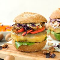 Zusehen ist ein vegetarischer Burger mit Tofu Bratling auf einem Holzbrett