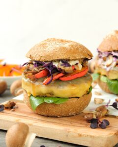 Zusehen ist ein vegetarischer Burger mit Tofu Bratling auf einem Holzbrett