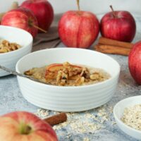Zusehen ist ein veganes Apfel Porridge mit Zimt und Walnüssen in einer Porzellanschale