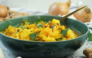 Hier ist ein vegetarischer Weißkohleintopf in einer blauen Schale und Sojasoße zu sehen