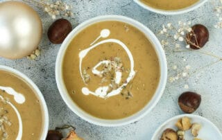 Auf dem Bild zusehen ist eine Vegane Maronensuppe mit Kartoffel auf einem herbstlich dekorieren Tisch