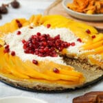 Hier ist ein vegane Rohkost Torte mit Mango und Granatapfelkernen zusehen