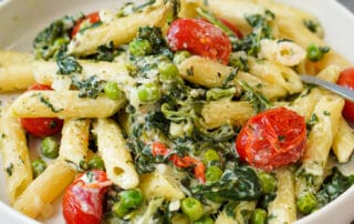 Auf dem Bild ist eine Pasta mit Spinat, Tomaten und Feta zusehen